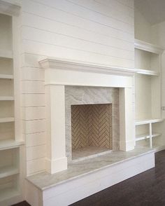 an empty living room with a fireplace and bookcases