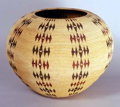 a woven vase with red and black designs on the outside, sitting on a white surface