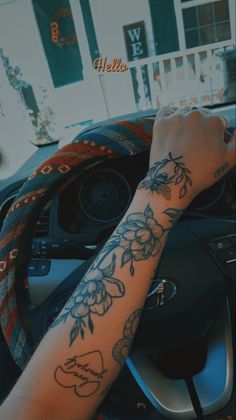 a person driving a car with a tattoo on their arm