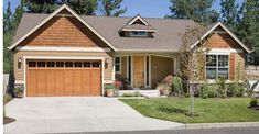 a brown house with two garages and trees in the background