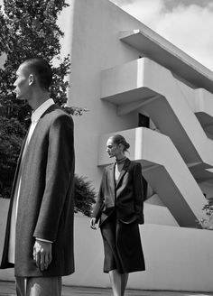 black and white photograph of man and woman walking in front of an art deco building