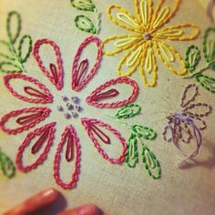 someone is stitching some flowers on a piece of cloth