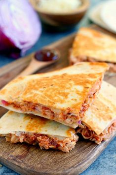 two quesadillas cut in half on a cutting board next to an onion