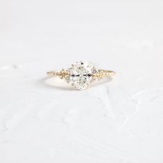 an oval cut diamond ring with three smaller diamonds on the band, set in yellow gold