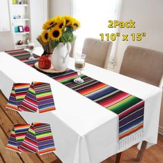 the table is set with sunflowers in vases on it and a colorful striped runner