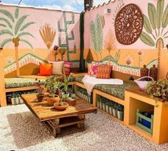 an outdoor seating area with plants and potted plants on the tables, in front of a painted wall