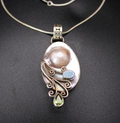 This beautiful large solid silver Sajen pendant, circa the 1990s, features a stunning mabe pearl at its centre, surrounded by intricate applied decoration. The pendant is further enhanced by the addition of a vibrant opal and sparkling green Peridor, creating a striking contrast against the silver. The craftsmanship reflects Sajen's renowned artistry, making this piece both elegant and unique. Paired with a matching chain, this pendant is a perfect statement accessory for those who appreciate ex Silver Pendant Pearl Necklace With Gemstone, Mabe Pearl, Chain Loop, Seashell Jewelry, Green Peridot, Snake Chain, Timeless Beauty, Jewelry Necklace Pendant, Opal