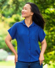 a woman with her hands on her hips standing in front of trees and looking up at the sky