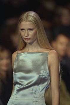 a model walks down the runway in a silver dress with long blonde hair and bangs