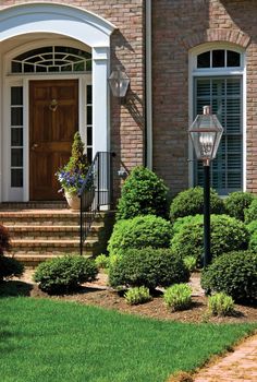 a large brick house with lots of windows and bushes around it's front door