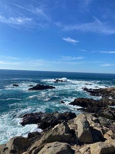 the ocean and rocky shore line under a blue sky