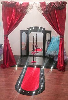 a room with red curtains and lights on the floor, including a black trampoline