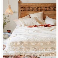 the bed is made with white linens and fringed pillows on top of it