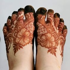 two feet with hendi tattoos on their legs and hands, both decorated with flowers