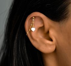 a close up of a person's ear wearing a gold chain and heart earrings