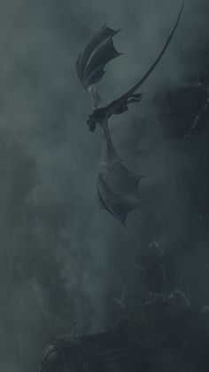 a dragon is flying through the air in front of some foggy clouds and water