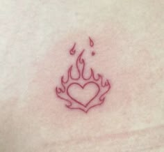 a small heart tattoo on the chest with flames coming out of it's center