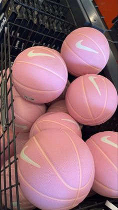 several pink basketballs are stacked up in a shopping cart