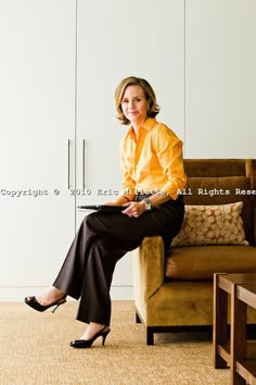 a woman sitting on top of a couch in a living room next to a brown chair