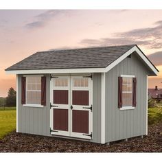 a small shed with two windows and shutters on the doors is shown at sunset