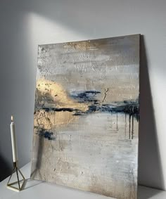 an abstract painting on canvas with a candle next to it