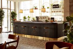 a bar with stools and plants behind it