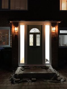 a front door is lit up at night with light coming through the window and covering the ground