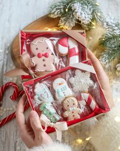 someone is holding up some christmas cookies in a box