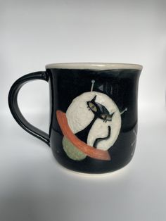 a black and white coffee cup with a cat on it