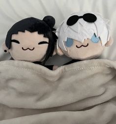 two stuffed dolls are wrapped in a blanket