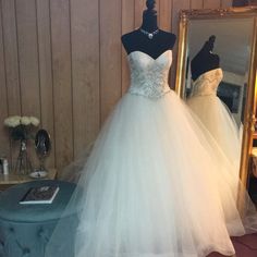 a wedding dress on display in front of a mirror