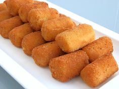 several pieces of deep fried food on a white plate with blue wall in the background