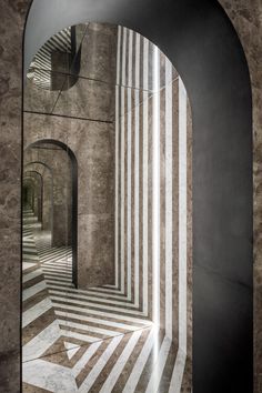 an arched doorway leading into a room with striped walls and floor tiles on the wall