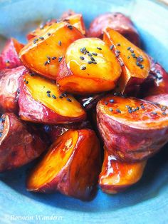 a blue bowl filled with sliced up peaches covered in sesame seeds and seasoning