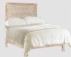 the bed is made with white linens and has an intricate headboard on it