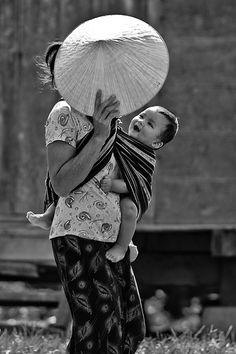 a woman holding a baby in her arms with an umbrella on top of her head