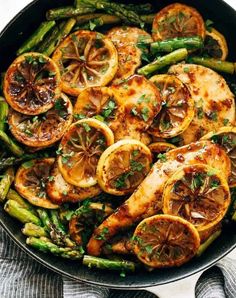 chicken, asparagus and oranges in a skillet with lemon slices on top