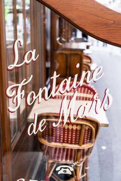 the reflection of chairs and tables in a shop window with french writing on it that says la fortaine de marie