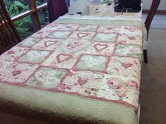 a bed with a pink and green quilt on it's headboard next to a window