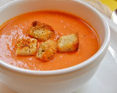 a white bowl filled with soup and croutons