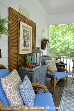 a porch with wicker chairs and blue cushions on the front porch, along with potted plants