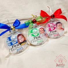 three christmas ornaments with ribbons and bows on a white sheet, one for the first time