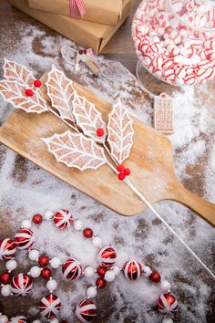 a wooden board with candy canes and leaves on it next to some candies