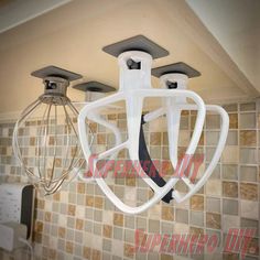 two kitchen mixers hanging from the ceiling in a kitchen with tiled walls and backsplash