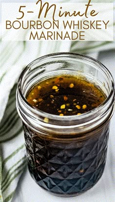 a glass jar filled with bourbon whiskey and garnished with yellow mustard on top