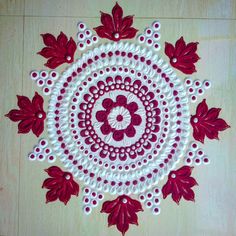 a red and white doily with flowers on it sitting on a wooden table top