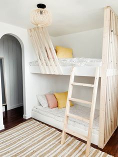 a room with bunk beds and a rug on the floor in front of two wooden ladders