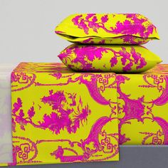 three pillows stacked on top of each other in front of a yellow and pink pillow case