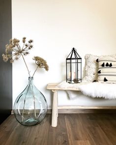 a vase with flowers sitting on a table next to a pillow and a candle holder