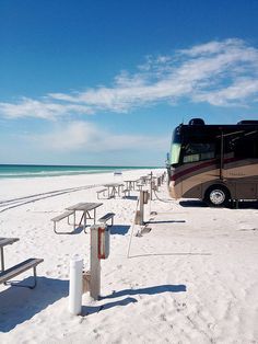 an rv parked on the beach next to picnic tables